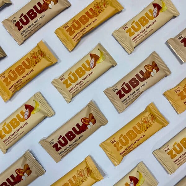 Barritas surtidas "de frutas y frutos secos con proteína de arveja" en envoltorios beige, amarillo y marrón dispuestos en diagonal sobre fondo blanco.